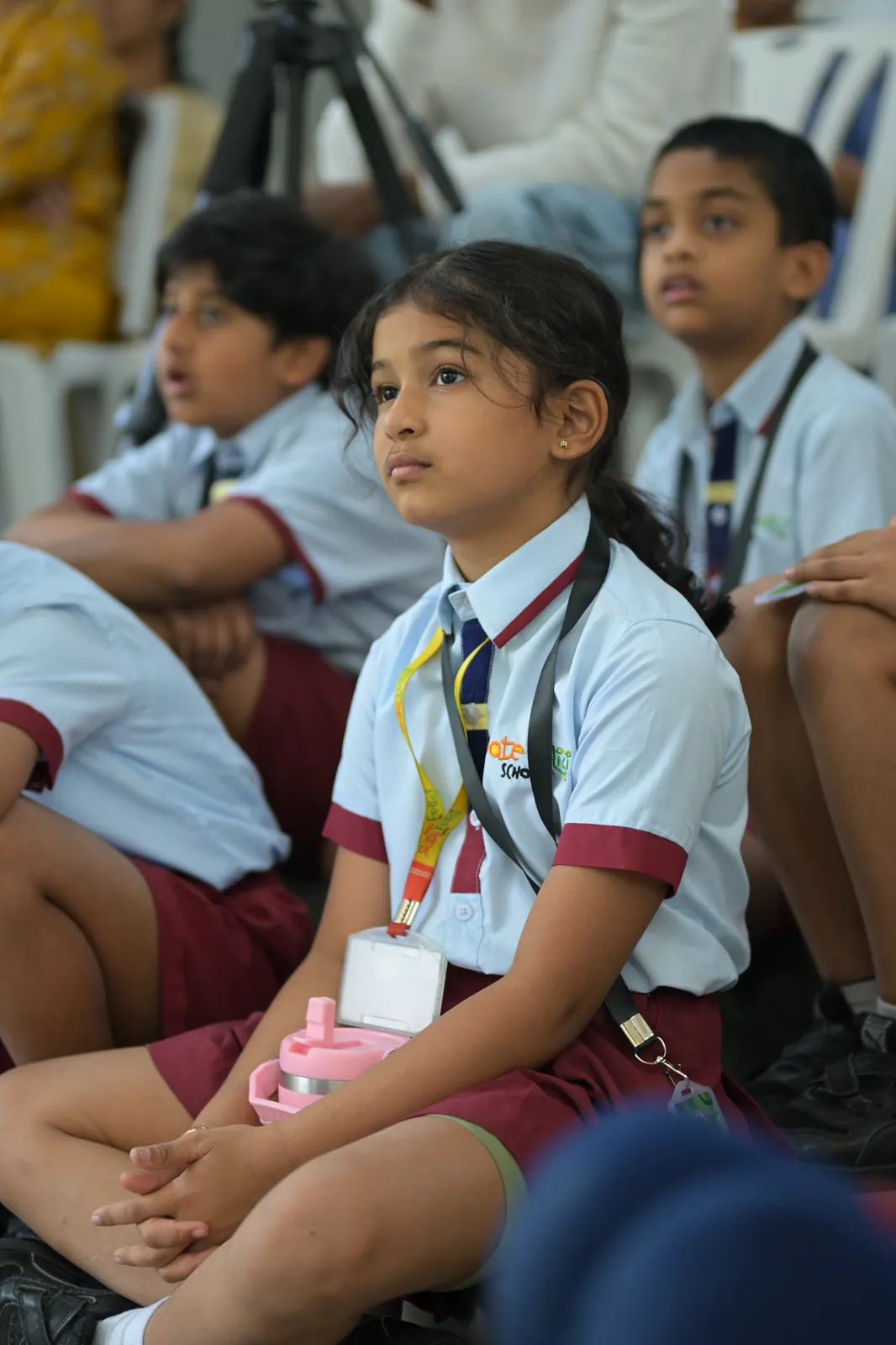 A student listening intently from the audience during a Vivencia session, classmates seated either side of her
